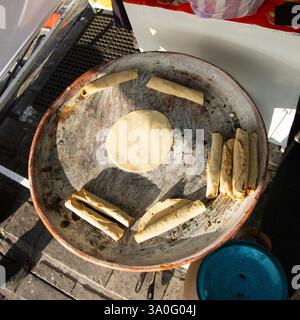 Eine Frau, die Tortillas, Flautillas und mexikanische Memelas auf einem comal auf einer Straße in Oaxaca kocht. Stockfoto