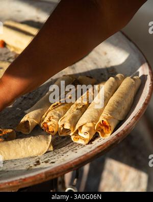 Eine Frau, die Tortillas, Flautillas und mexikanische Memelas auf einem comal auf einer Straße in Oaxaca kocht. Stockfoto