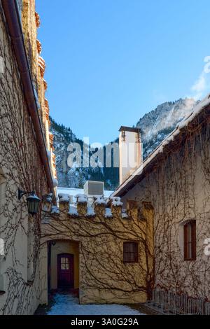 Majestätische mittelalterliche Burgtürme über verschneiten Alpenlandschaften, beleuchtet vom frühen Morgen Licht gotische Architektur Meisterwerk dominiert Winter Wonde Stockfoto