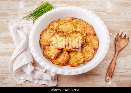 Knusprige Kartoffelpfannkuchen in großer Servierschale mit Schnittlauchfleisch Stockfoto