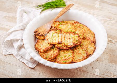 Knusprige Kartoffelpfannkuchen in großer Servierschale mit Schnittlauchfleisch Stockfoto