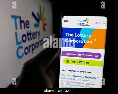 In dieser Abbildung befindet sich ein Mobiltelefon mit der Webseite des australischen Unternehmens Lottery Corporation Limited auf dem Bildschirm mit Logo. Stockfoto