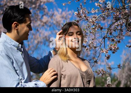 Ein junges lateinamerikanisches Paar, das im Frühling einen romantischen Moment unter einem blühenden Mandelbaum genießt Stockfoto