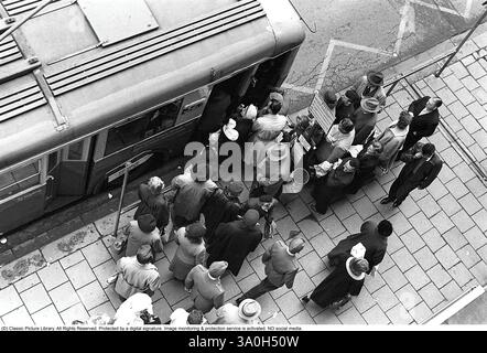 Bushaltestelle in Stockholm 1953. Die Leute warten an der Bushaltestelle auf den Bus. Der Bus 32 auf der Linie Fleminggatan-Fridhemsplan hält an und die Leute steigen in den Bus. Der Bus wurde mit Elektrizität betrieben und hieß Trolleybus, er bezieht seine Energie aus Oberleitungen mit federbelasteten Trolleymasten. Stockholm 1953, Kristoffersson Ref. 1-12 Stockfoto