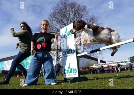 Die Paralympierin Ellie Simmonds, die in der Present-Line-up für die Crufts TV-Show neu angekündigt wurde, bejubelt den englischen Springer Spaniel Leah, der während der offiziellen Veröffentlichung der Crufts Dog Show 2025 im NEC Birmingham über ein Hindernis springt. Bilddatum: Dienstag, 4. März 2025. Stockfoto