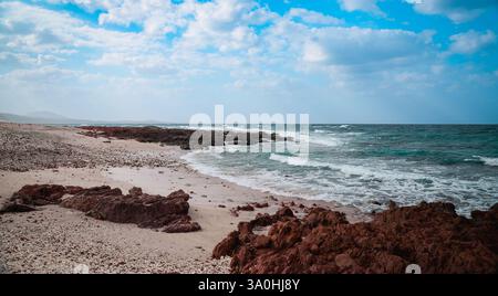 Wellen brechen gegen die felsige Küste von Socotra und enthüllen einen ruhigen Strand umgeben von einzigartigen geologischen Besonderheiten. Stockfoto