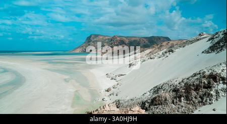 Riesige weiße Sanddünen treffen auf türkisfarbenes Wasser auf Socotra Island, das einzigartige geologische Besonderheiten unter hellem Himmel zeigt. Stockfoto