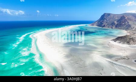 Hellblaues Wasser trifft auf weichen weißen Sand in Socotra, was die einzigartigen geologischen Formationen und die natürliche Schönheit der Insel hervorhebt. Stockfoto