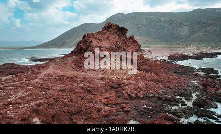 Besucher bestaunen die markanten roten Felsformationen und die atemberaubende Aussicht auf die Küste von Socotra Island bei Tageslicht. Stockfoto
