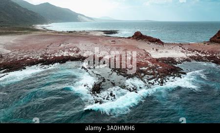 Wellen brechen gegen die zerklüftete Küste von Socotra Island und enthüllen ihre einzigartigen geologischen Besonderheiten und landschaftlichen Schönheiten. Stockfoto