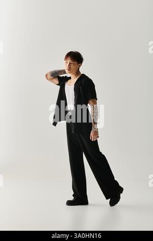 Ein junger, gutaussehender asiatischer Mann zeigt seinen einzigartigen Stil, während er drinnen eine elegante Pose anschlägt. Stockfoto