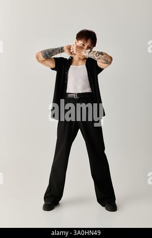 Ein junger und gutaussehender asiatischer Mann präsentiert sein stilvolles Outfit vor einer minimalistischen Kulisse. Stockfoto