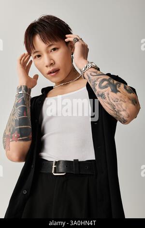 Selbstbewusster junger Mann zeigt Tattoos in einem stilvollen Outfit und künstlerischen Ambiente. Stockfoto
