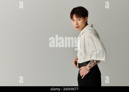 Selbstbewusster junger Mann zeigt seinen einzigartigen Stil und seine Tattoos in einem modernen und minimalistischen Ambiente. Stockfoto