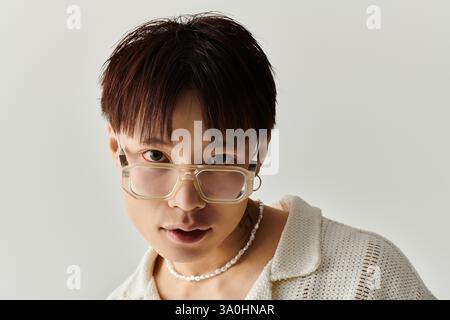 Selbstbewusster junger asiatischer Mann in schicken, weichen Farbtönen und Brillen zeigt seinen stilvollen Look. Stockfoto