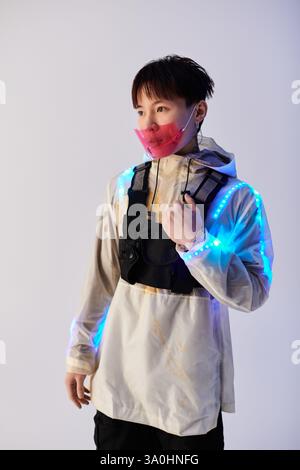Ein stilvoller junger asiatischer Mann zeigt selbstbewusst ein Outfit mit LED-Akzenten. Stockfoto