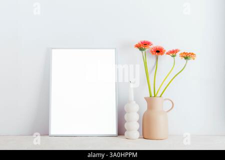 Mockup Bilderrahmen, Blumen in Vase und Kerze auf weißem Hintergrund. Stockfoto