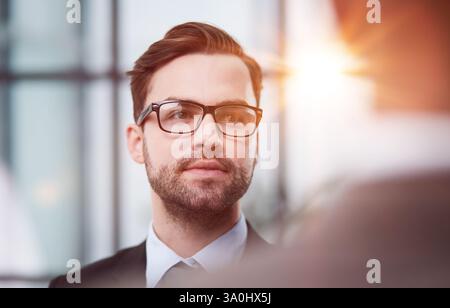 Geschäftsmann, der im Flur steht und mit einem Kollegen spricht Stockfoto