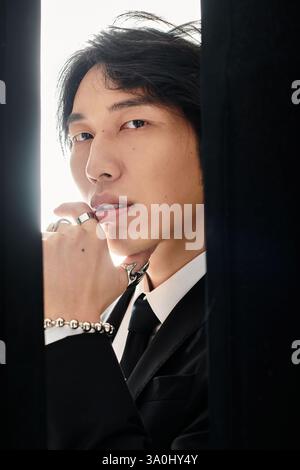 Ein stylischer junger asiatischer Mann in einem schicken Anzug posiert und zeigt seinen trendigen Look. Stockfoto