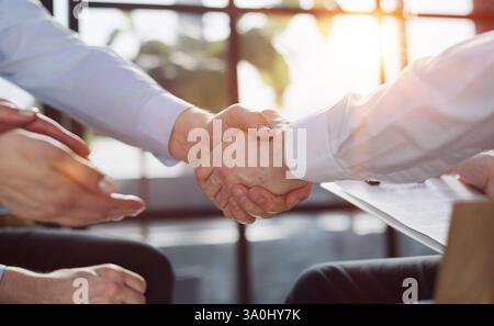 Im Büro: Nahaufnahme der Hände von Geschäftsleuten beim Unterzeichnen von Verträgen und Händeschütteln, um den Deal abzuschließen. Stockfoto
