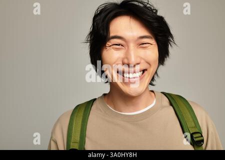 Ein stilvoller junger asiatischer Mann lächelt hell und strahlt Jugend in einer modernen Umgebung aus. Stockfoto