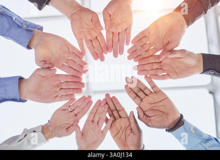 Junge Freiwillige legen ihre Hände wie ein echtes Team aufeinander, während sie im Büro einer Wohltätigkeitsorganisation stehen Stockfoto