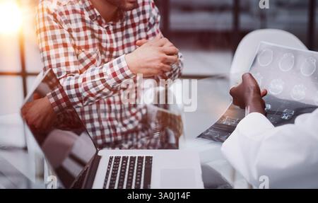 Der Arzt und der Patient an der Rezeption besprechen das Röntgenbild Stockfoto