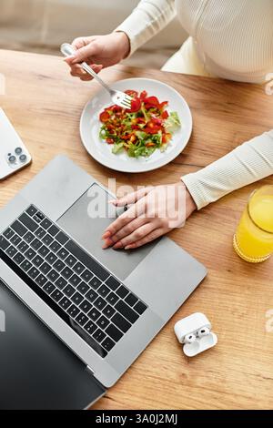 Blick von oben auf die Frau sitzt an einem Küchentisch und genießt ein gesundes Frühstück mit lebhaftem Salat. Stockfoto