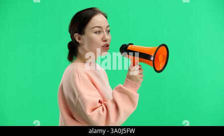 Frau, Nahaufnahme, auf grünem Hintergrund, mit einem Megaphon Stockfoto