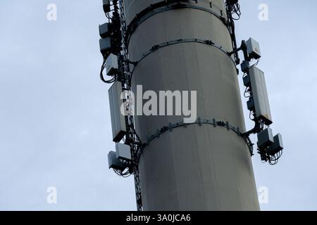 Der Telekommunikationsturm aus Stahl erhebt sich gegen einen bewölkten Himmel, der mit verschiedenen Antennen und Geräten geschmückt ist. Diese Struktur spielt eine entscheidende Rolle bei der Unterstützung der drahtlosen Kommunikation in der Stadt. Stockfoto