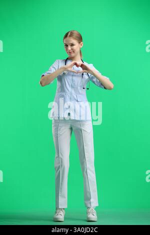 Der Arzt zeigt in voller Höhe auf grünem Hintergrund das Herz Stockfoto