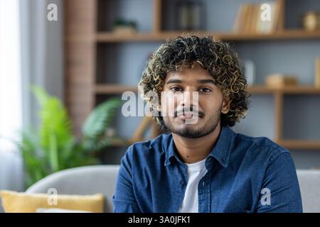 Porträt eines hübschen jungen Mannes mit lockigen Haaren, der ein Jeansshirt trägt und direkt in die Kamera blickt. Stockfoto