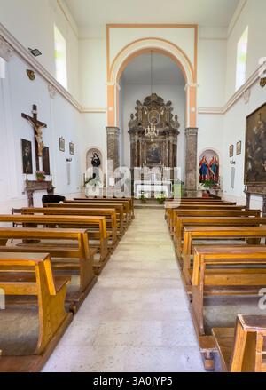 Taormina, Sizilien, Italien - 5. Juli 2024: Kirche Santa Domenica. Blick von hinten auf den Hochaltar und seine Reredos. Einfache Bänke. Statue der Heiligen Rita Stockfoto