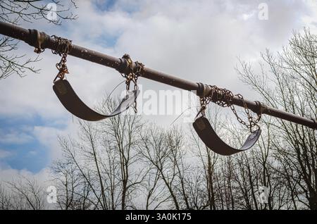 Paar Schaukelsitze außerhalb der Reichweite an Ketten gegen den Himmel Stockfoto