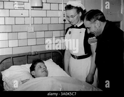 Jüngster Gewinner von G.C. - Rettet Brothers from Blazing Room -- der fünfzehnjährige Jack Bamford, der jüngste Träger des George Cross (ziviles Äquivalent des V.C.), im Bett im General Hospital, Nottingham, wo er sich von den Verbrennungen erholt, die er bei dem heldenhaften Akt erhielt, der den Preis gewann. Mit Jack sind Schwester M. Odey und Reverend A. Doxey, der versprochen hat, den Jungen zu begleiten, wenn er zum Buckingham Palace geht, um das George-Kreuz zu empfangen. Letzten Oktober stürzte Jack durch Flammen, um zwei seiner Brüder zu retten, die im Schlafzimmer ihres glühenden Hauses in Newthorpe, Nottinghamshire, gefangen waren. Er W Stockfoto