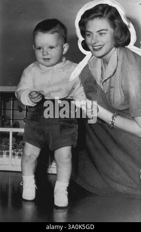 Bereit für die erste Geburtstagsfeier – Roberto Rossellini, der Sohn der Schauspielerin Ingrid Bergman und des italienischen Regisseurs Roberto Rossellini, sieht sich der Kamera für ein Geburtstagsbild gegenüber, während seine Mutter zustimmend im Rossellini Apartment in Rom am 2. Februar zusieht. Der Junge ist verkleidet für die Quiet Party, die seinen ersten Geburtstag feiert. Einer seiner Gäste war Renzo Rossellini, sein Halbbruder. Februar 1951. (Foto von AP Wirephoto) Stockfoto