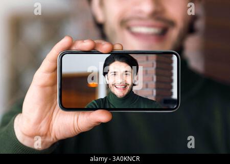 Junger schöner Mann, der Selfie beim Kaffeetrinken nimmt Stockfoto