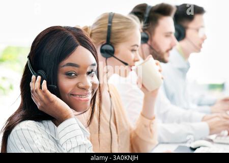 Gruppe von Callcenter-Vertretern mit Headsets, die an Computern im hellen Büro arbeiten, Platz für Text Stockfoto
