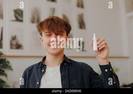 Kranker, kranker oder allergischer junger Mann, der zu Hause ein Nasenspray hält Stockfoto