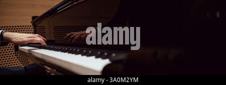 Die Hände eines Pianisten spielen anmutig das Klavier, mit einer sanften Reflexion auf der Oberfläche des Instruments, die das Wesen des musikalischen Ausdrucks einfängt. Stockfoto