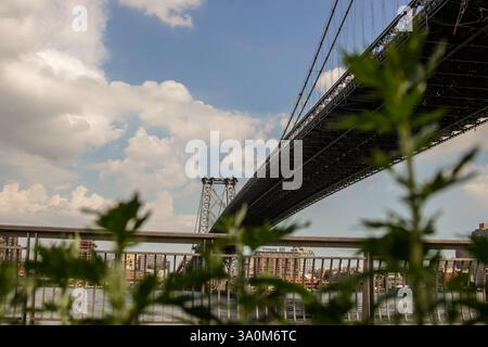Ein dramatischer, flacher Blick auf die williamsburg Bridge in New York City mit kontrastierenden Glas-, Stahl- und Betonkonstruktionen. Stockfoto