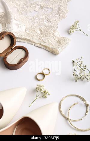 Eheringe, Ohrringe, Holzbox, Kleid und Absätze auf weißem Hintergrund Stockfoto