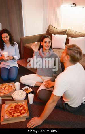 Freunde, die einen ungezwungenen Abend mit Pizza, Popcorn und tollen Gesprächen zu Hause genießen Stockfoto