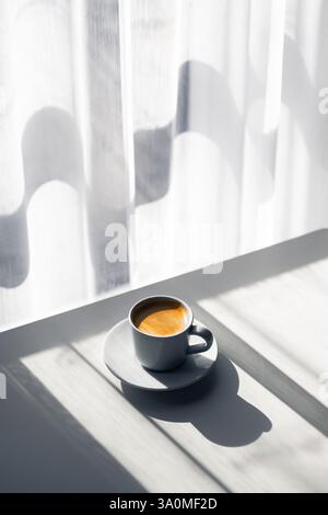 Aromatischer Espresso in einer Tasse auf einem Holztisch, beleuchtet durch sanftes Tageslicht. Inspiration für die Kaffeefotografie Stockfoto