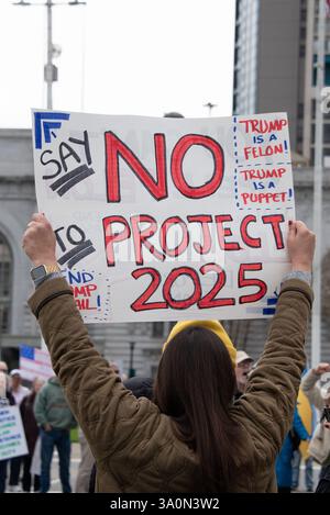 San Francisco, USA. März 2025. Eine Frau hält ein Schild mit der Aufschrift „Sag Nein zu Projekt 2025“, während sich Demonstranten am Civic Center Plaza vor dem Rathaus von San Francisco versammeln, um gegen die Befehle von Präsident Trump und die Aktionen von Elon Musk und seinem DOGENTEAM zu protestieren. Quelle: Shelly Rivoli/Alamy Live News Stockfoto