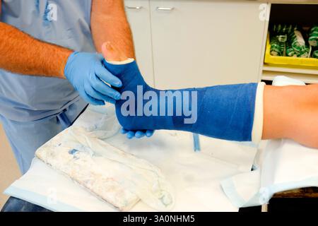 Ein Arzt legt einem jungen Fußballspieler das gebrochene Bein nach einer Sportverletzung in Gips Stockfoto