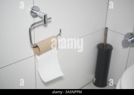 Toilettenpapierrollenhalter mit leerem Papprohr in der Toilette Stockfoto