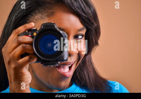Junge schwarze Fotografin lächelt und macht Fotos mit professioneller dslr-Kamera Stockfoto