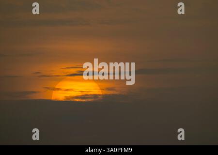 Wunderschöne große Sonne untergeht mitten in der Wolke, isolierte riesige Sonne in der Dämmerung, magische Momente am Himmel Stockfoto