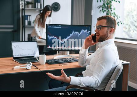 Tauschen Sie Diagramme auf dem Bildschirm aus. Zwei Mitarbeiter arbeiten im modernen Büro zusammen. Stockfoto